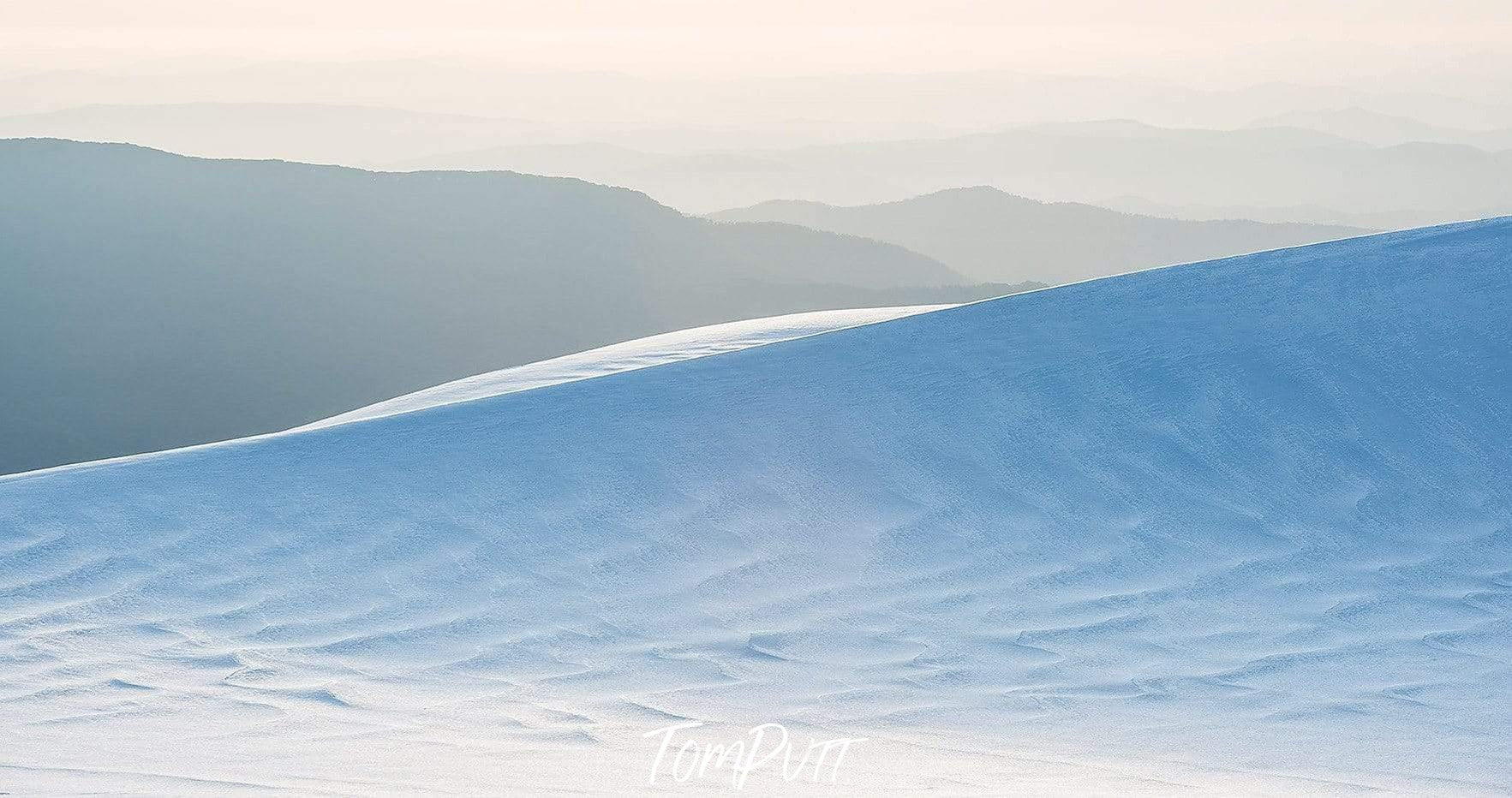 A beautiful afternoon view depicting a snowy smoke-colored mountain, and the dark dim mountains in the background, Snowy Mountains - New South Wales 