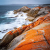 Shiny orange mountains walls with a bubbling seashore, Rocky Shoreline, Bay of Fires