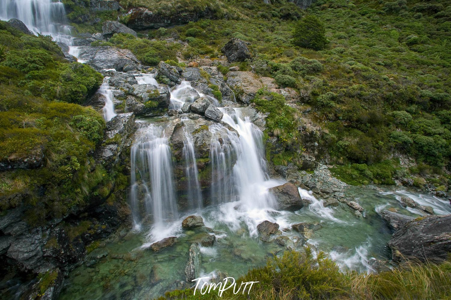 Long shot of nested waterfalls from a green hill point, Routeburn Falls, Routeburn Track - New Zealand