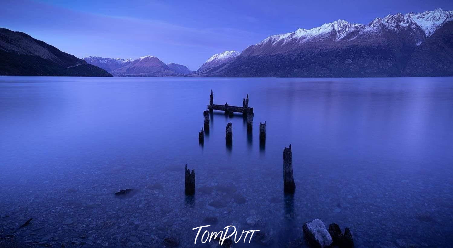 Small wooden sticks in the lake with some mountain walls behind, Ruined Jetty, Glenorchy New Zealand