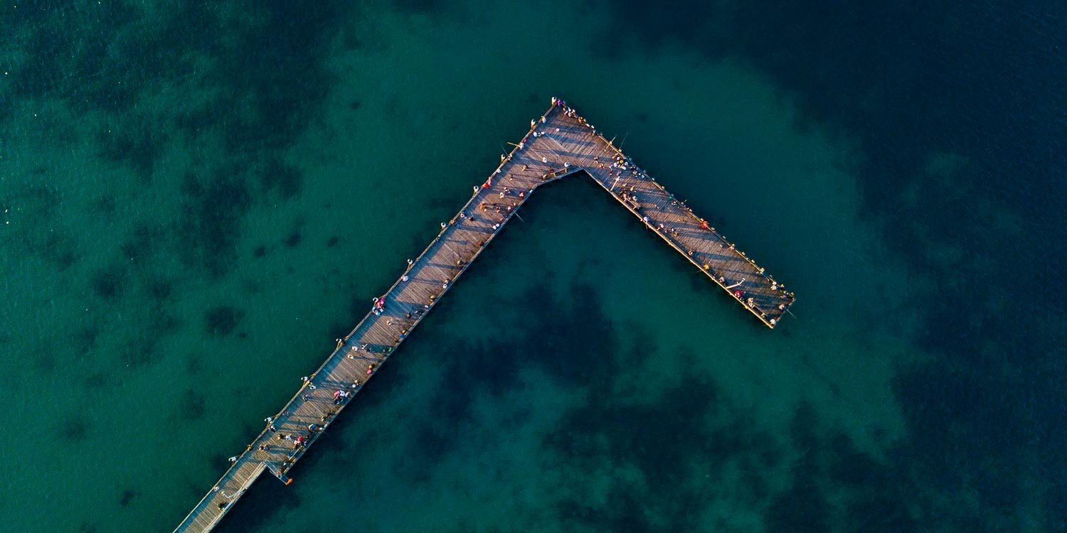 Aerial view of dark sea-green lake with a long wooden bridge over, Rye Pier from above - Mornington Peninsula VIC