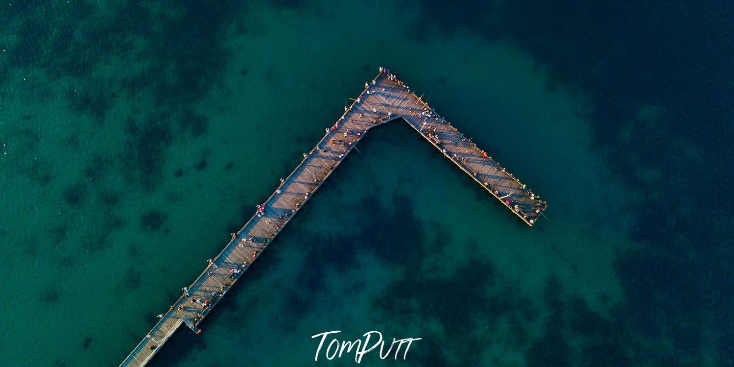 Aerial view of dark sea-green lake with a long wooden bridge over, Rye Pier from above - Mornington Peninsula VIC