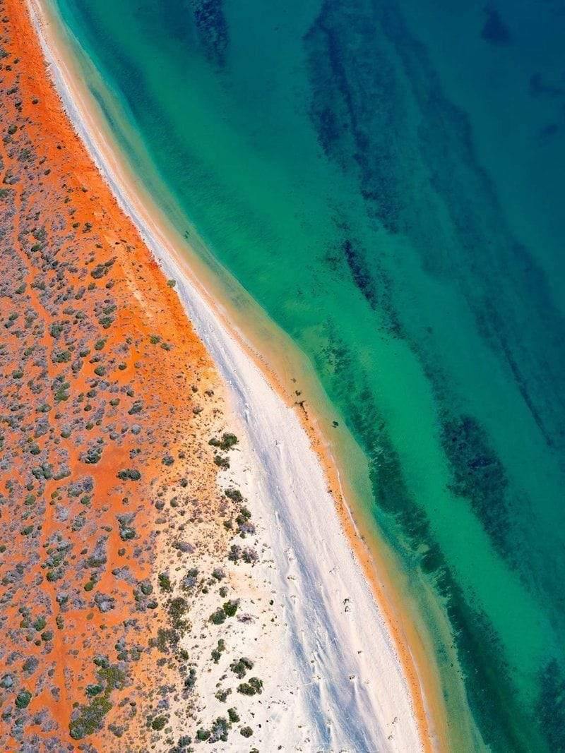 Aerial view of a dark sea-green ocean with an orangish land surface, Shark Bay #4