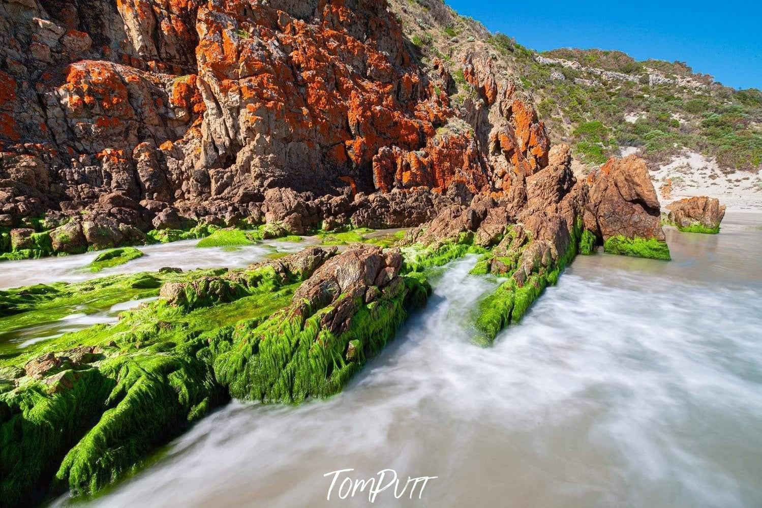 A shining mountain wall with a lake having fresh green plants and bushes over small stones, Snelling Beach - Kangaroo Island SA