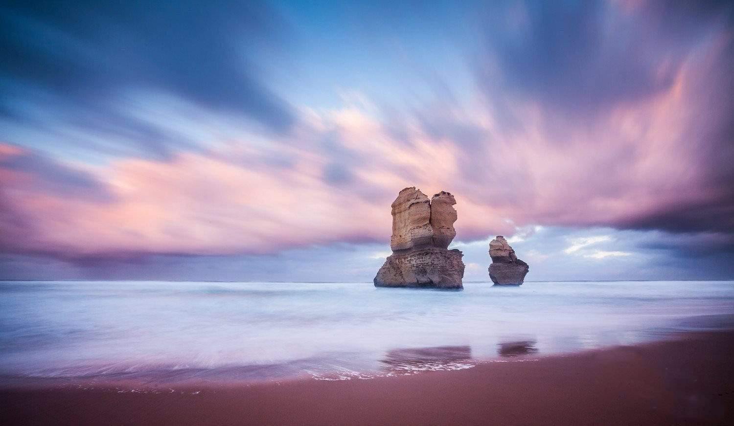 A standing couple of giant Stones with lilac-colored sky and shadow in the water, Standing Strong - Great Ocean Road VIC