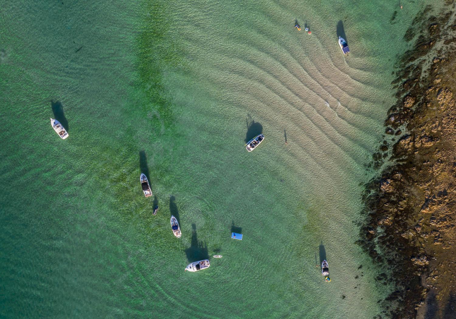 Aerial view of a calm sea with some boats over and a big mountain wall on the corner, Summer Ripples, Mt Martha - Mornington Peninsula VIC