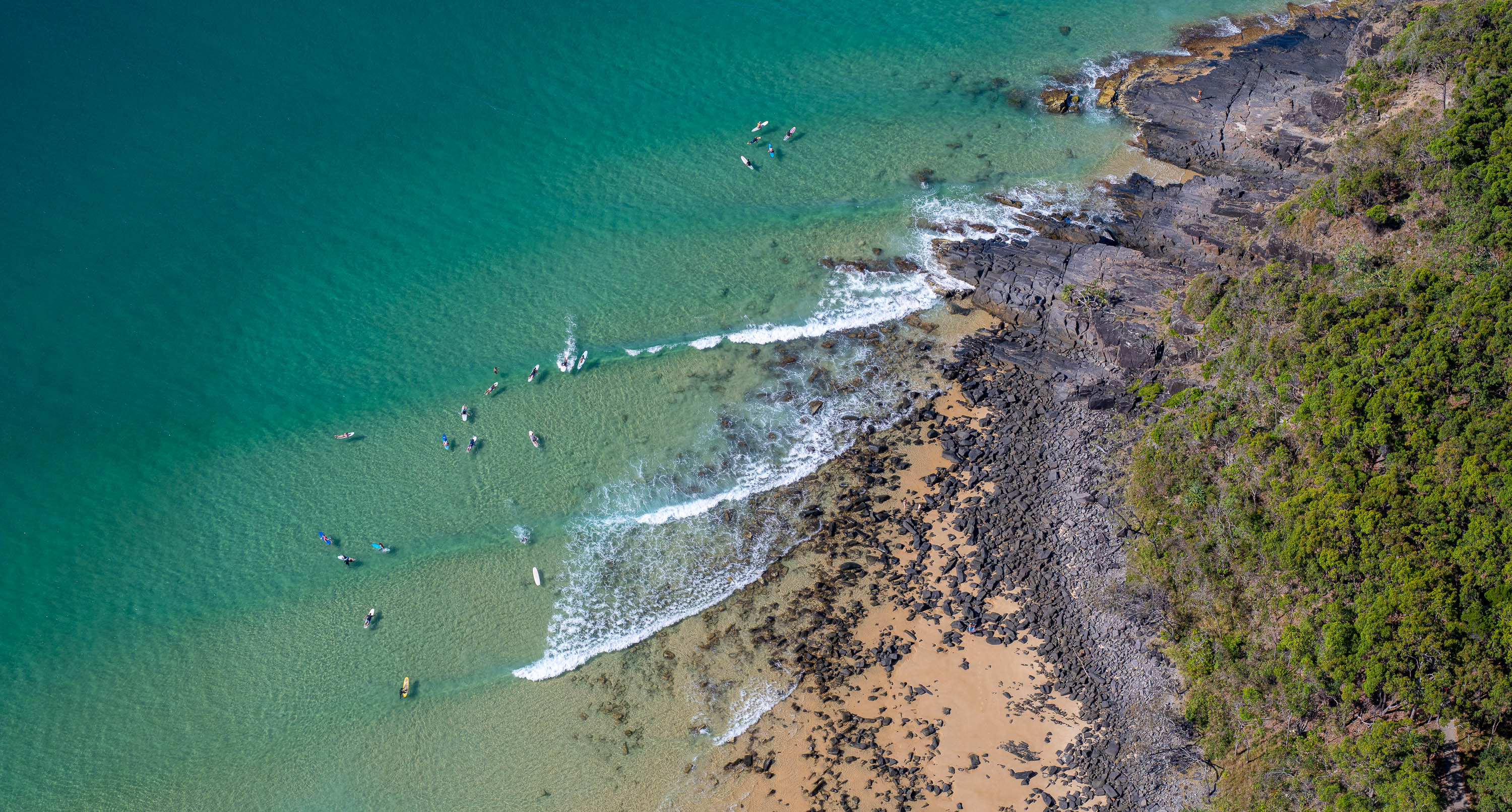 Aerial view of a giant green mountain wall with a beach below, Surf Break from above, Noosa National Park, Queensland
