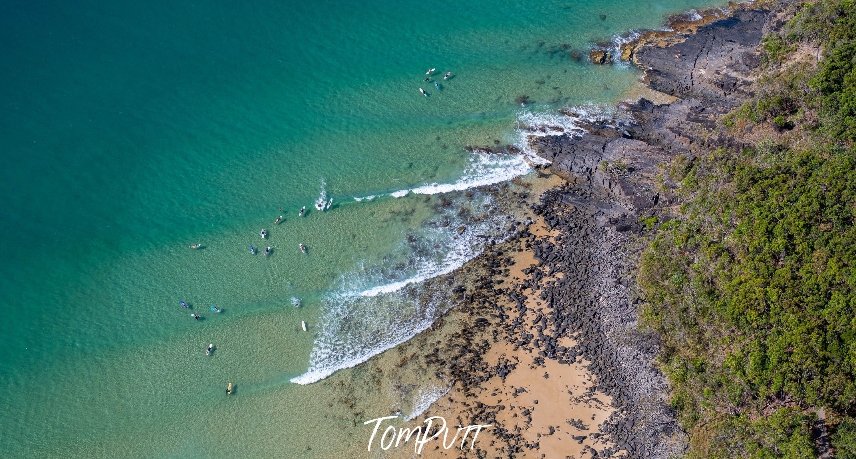 Aerial view of a giant green mountain wall with a beach below, Surf Break from above, Noosa National Park, Queensland