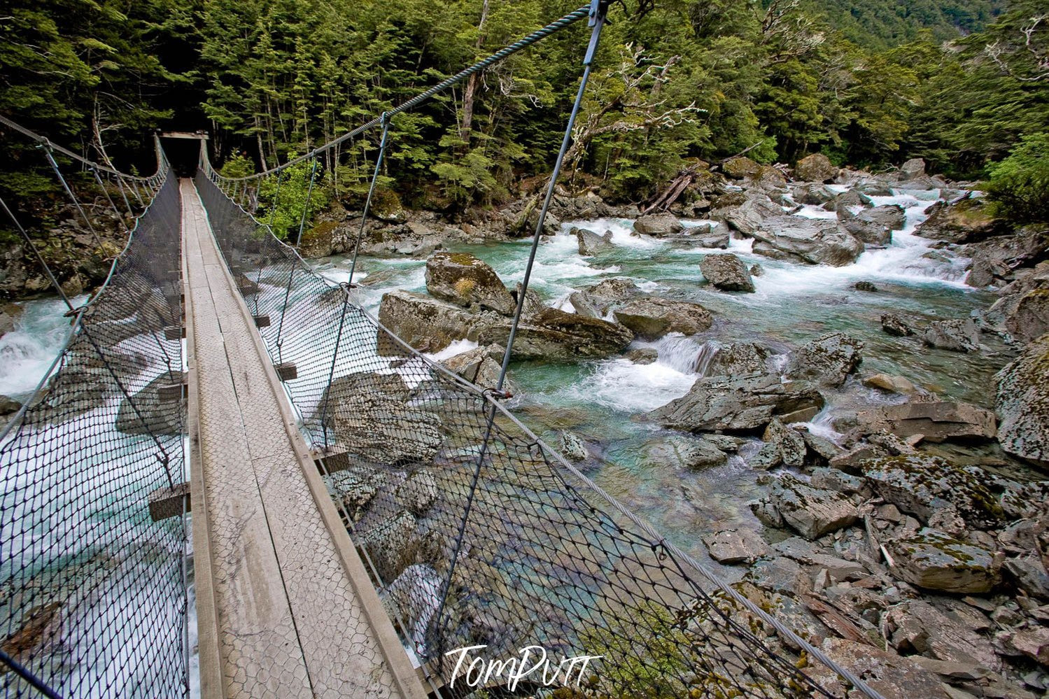 A bridge over a green watercourse with nested steel sidewalls, Swing Bridge over the Route Burn, Routeburn Track - New Zealand