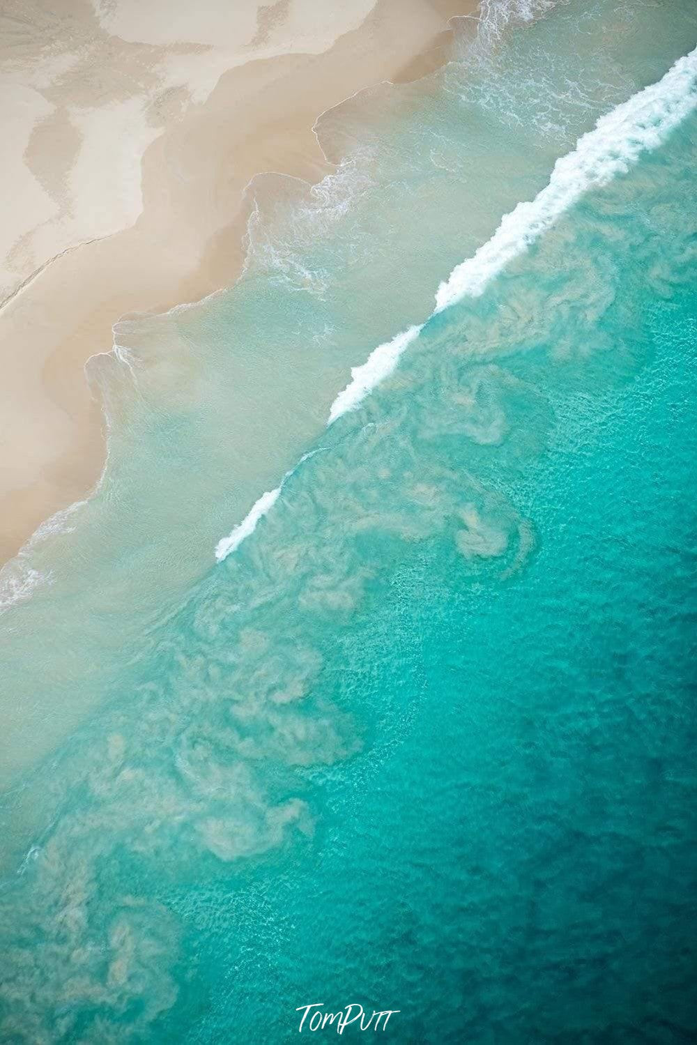 Aerial view of a huge ice-blue sea connecting with a beach-like land, Swirls