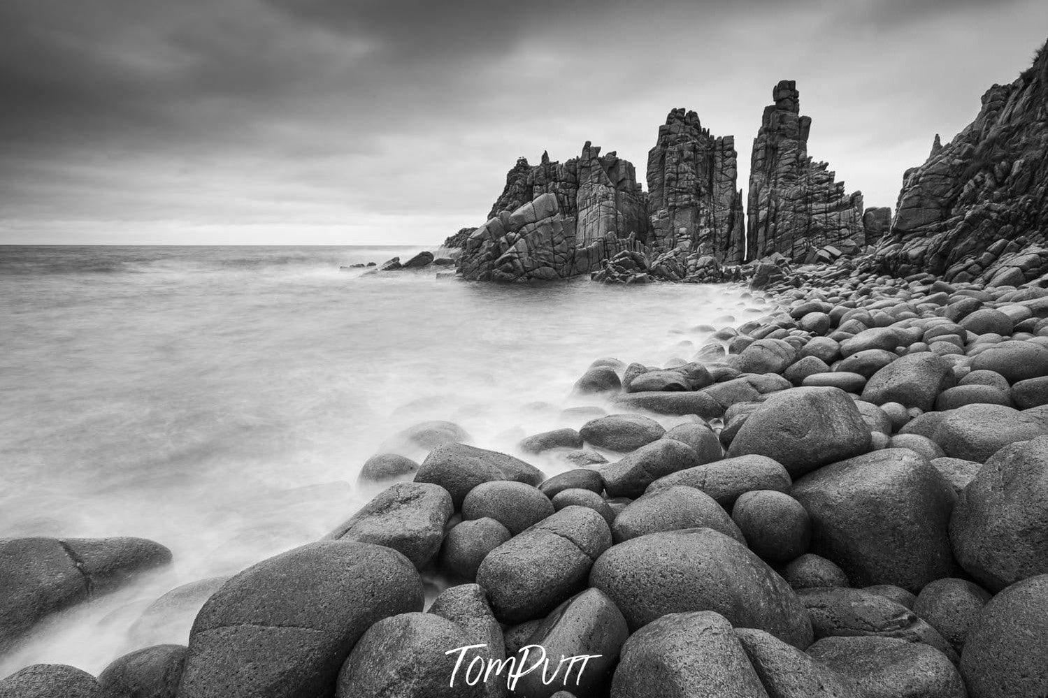 A beach with a lot of rounded stones and some standing sculpture of stones behind, The Pinnacles 2, Phillip Island