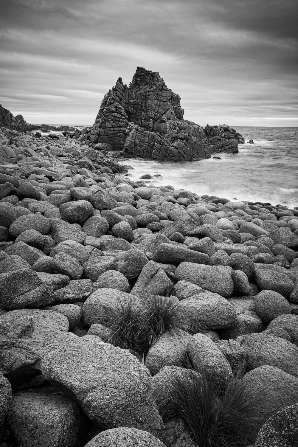 A beach with a lot of rounded stones and some standing sculpture of stones behind, The Pinnacles 7, Phillip Island