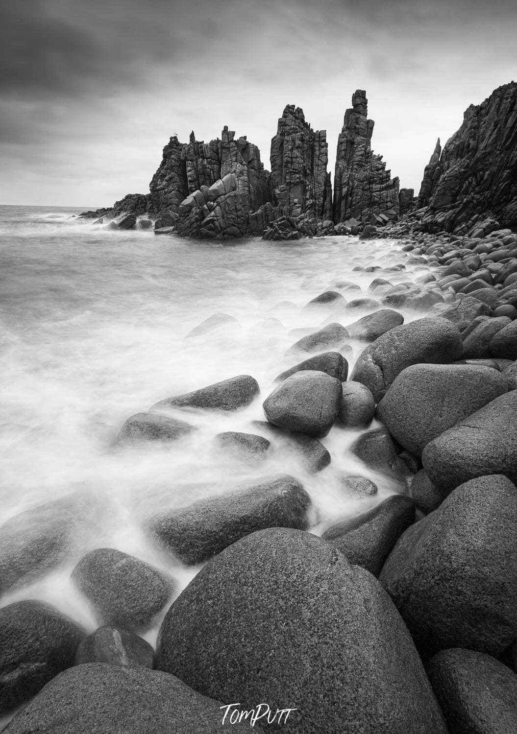 A beach with a lot of rounded stones and some standing sculpture of stones behind, The Pinnacles, Phillip Island