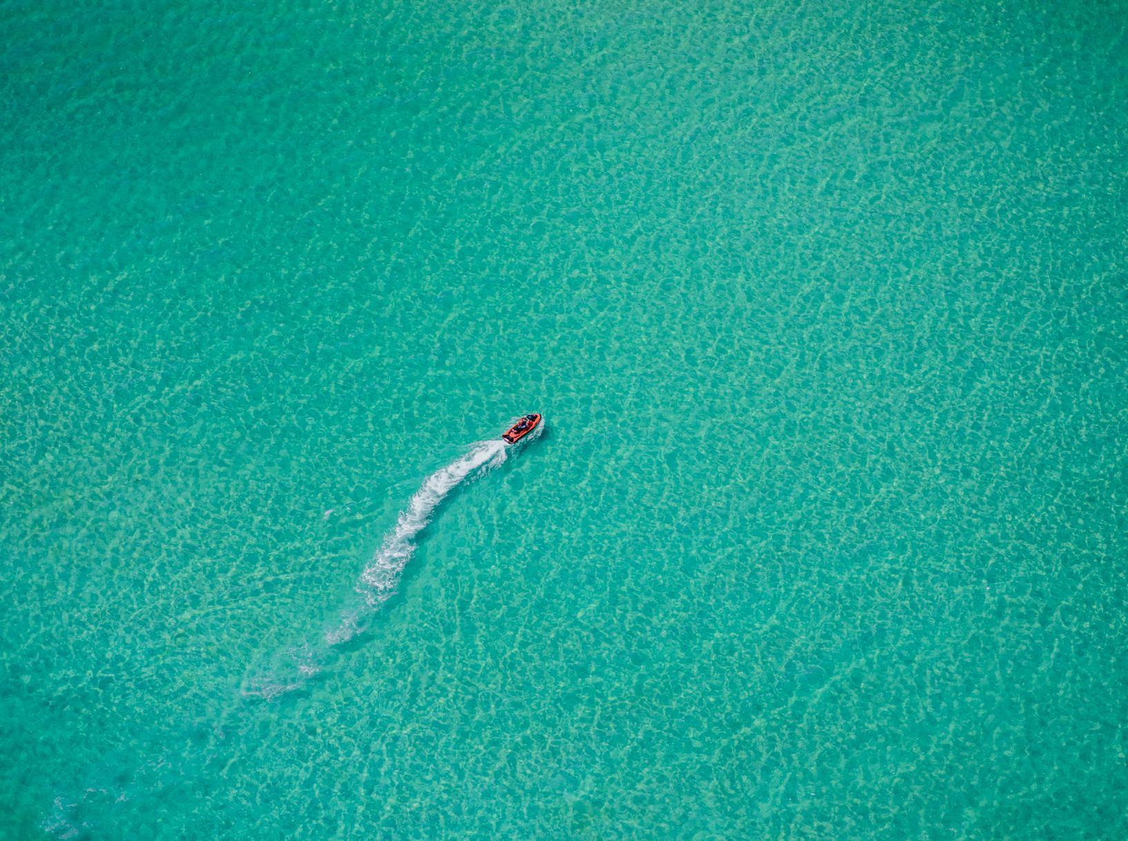 Aerial view of the ice-blue ocean with a boat passing over, Turquoise - Mornington Peninsula VIC 