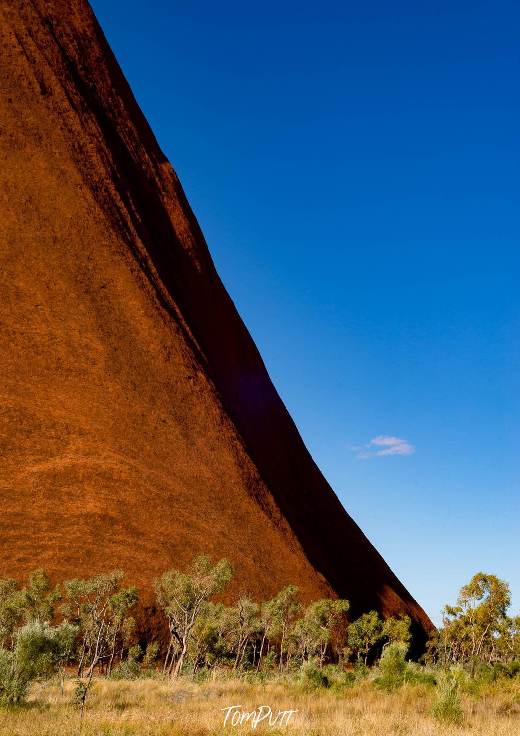 A pyramid-like high mountain wall with some plants on the base, Uluru Curves - Northern Territory