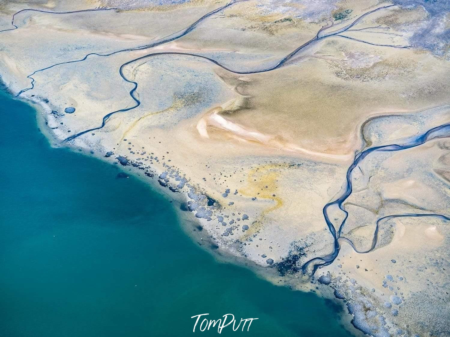 A beach-like sandy surface with some curvy lines over, and a connecting green-sea, Walvis Bay from above, Namibia