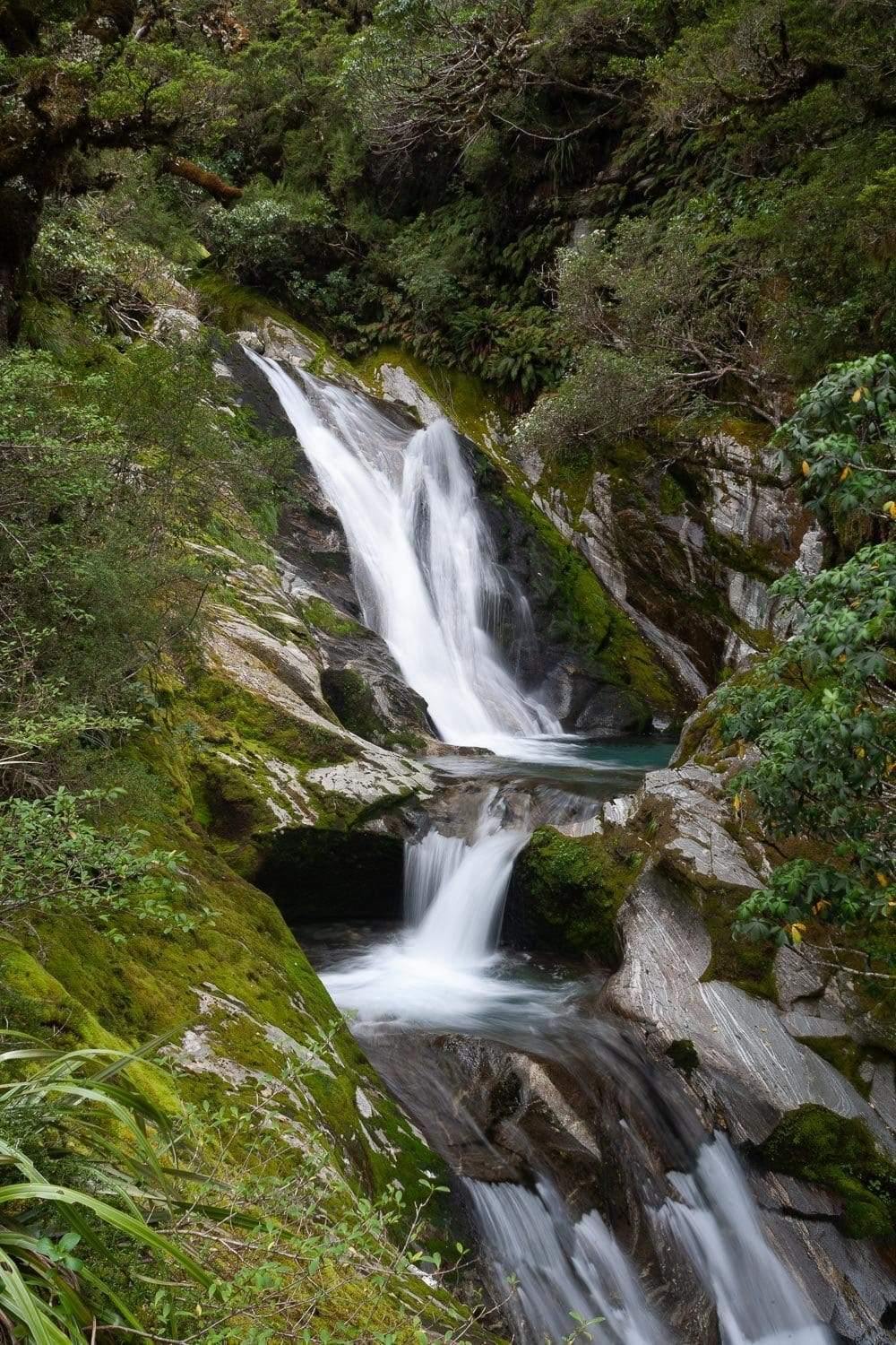 A long waterfall from a green hill mountain, Waterfall 6, Milford Track - New Zealand